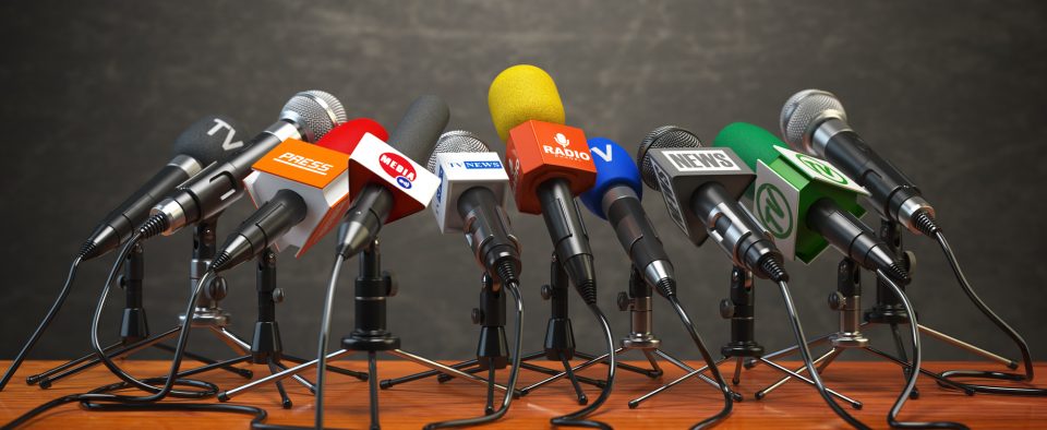 Press conference or interview on air. Microphones of different mass media, radio, tv and press prepared for conference meeting.